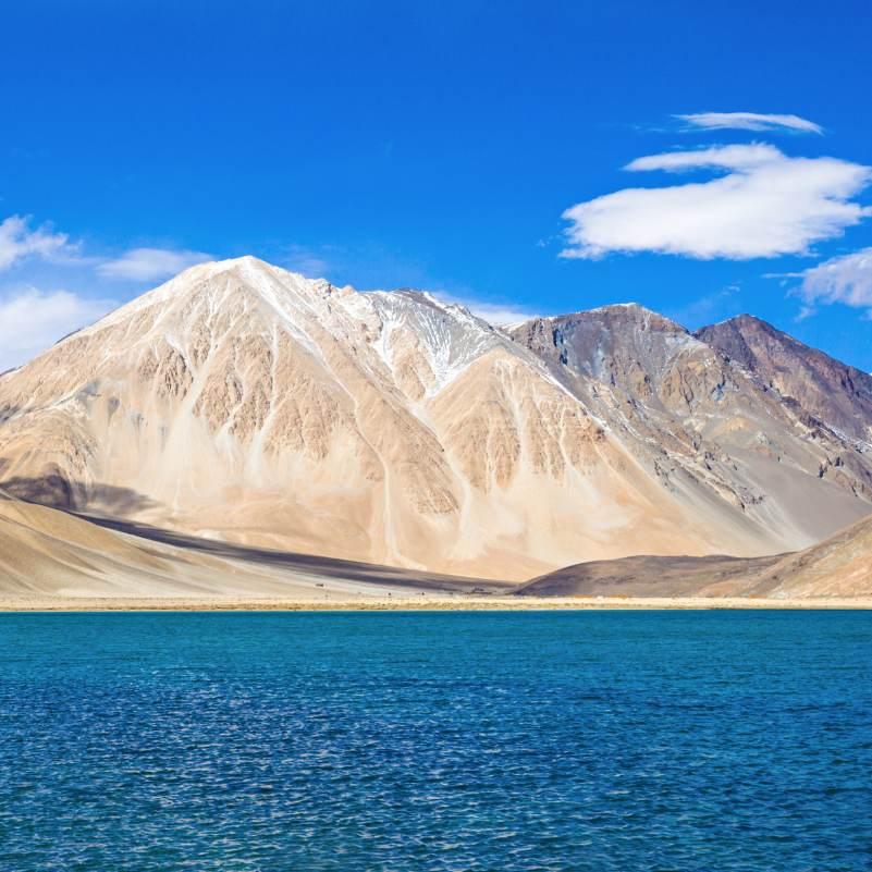 Still morning reflection on Pangong Lake before the wind picks up, the short early window most photographers plan their overnight stay around