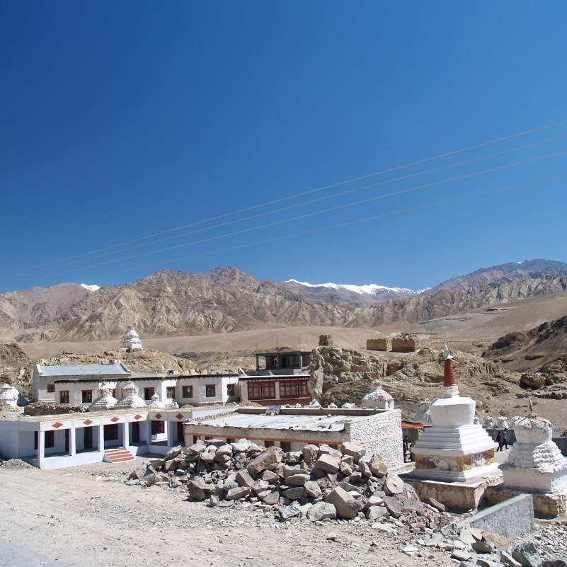 Whitewashed Alchi Monastery buildings with barren Ladakh mountains rising behind