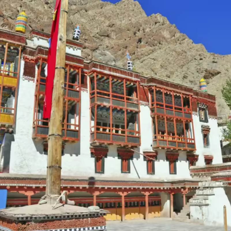 Courtyard of Hemis Monastery with traditional Ladakhi buildings, prayer flags, and the surrounding Himalayan ridges