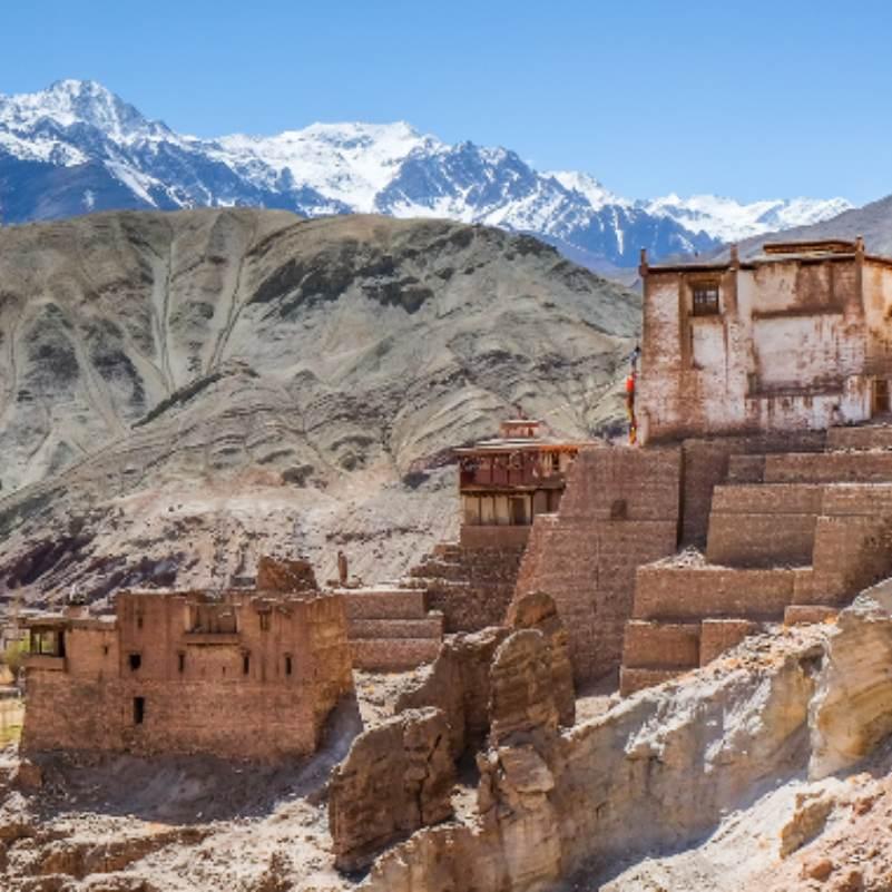 Courtyard inside the Alchi Monastery complex with mud walls and wooden doorways leading to the ancient temples