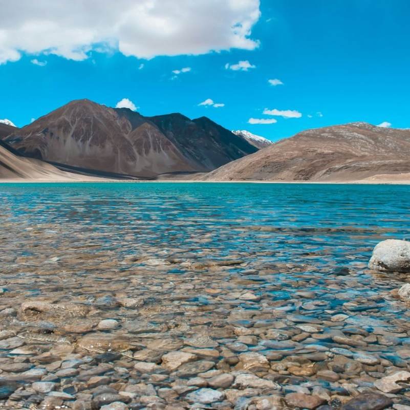 Pangong Tso Lake stretching between barren mountain walls in eastern Ladakh, the signature wide-angle view most travellers arrive for