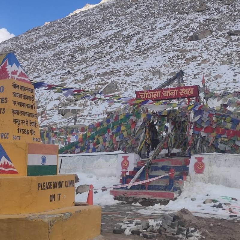 Prayer flags strung across the top of Chang La Pass with snow covered mountains behind