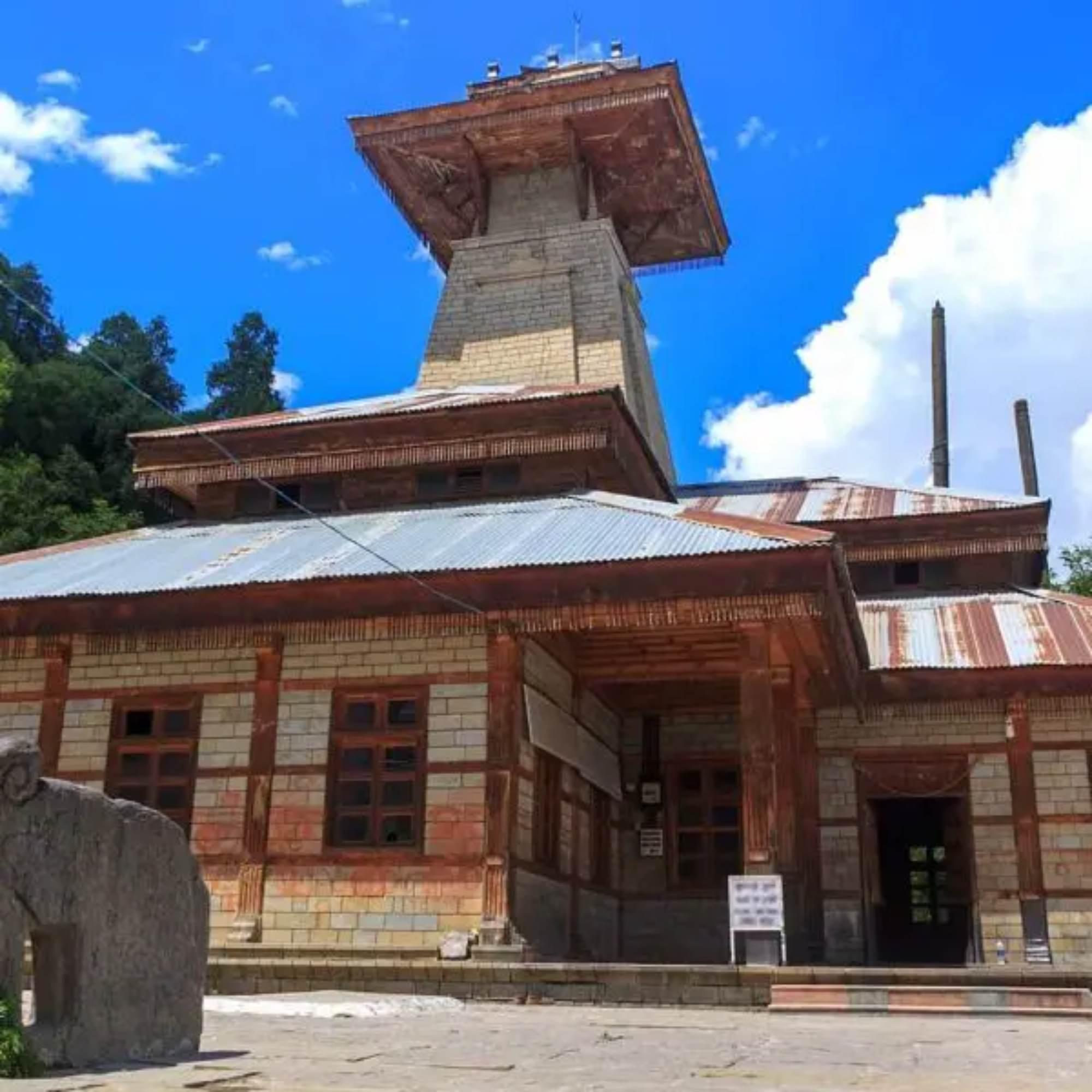 Peaceful view of Manu Temple with deodar trees and mountain backdrop in Old Manali