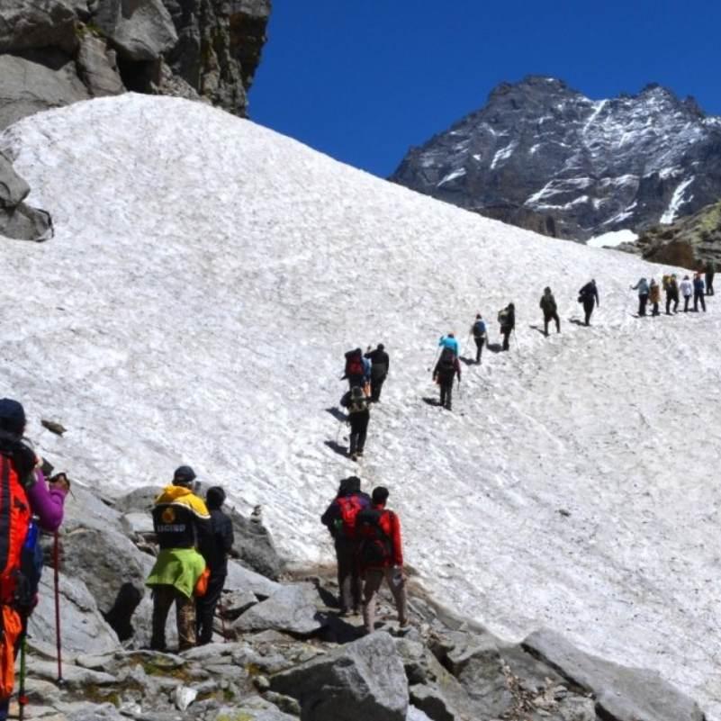 Trekkers crossing a glacial river with ropes on the Hampta Pass trail