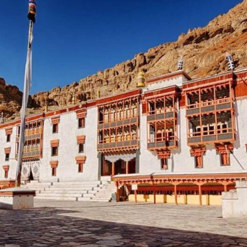 Prayer flags strung across the Hemis Monastery courtyard with monastery buildings in the background